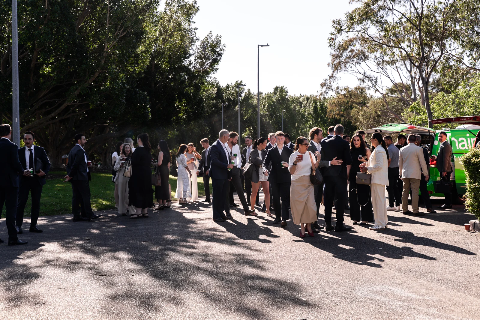 Guests gather outside the venue in the sunshine.